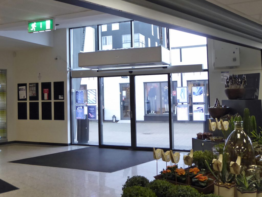 En ovanblåsande luftridå från RMK i en entré med blommor.