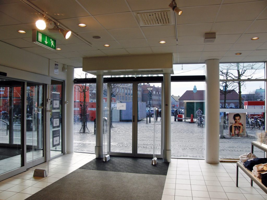 En sidoblåsande luftridå från RMK i en entré med nödskylt.