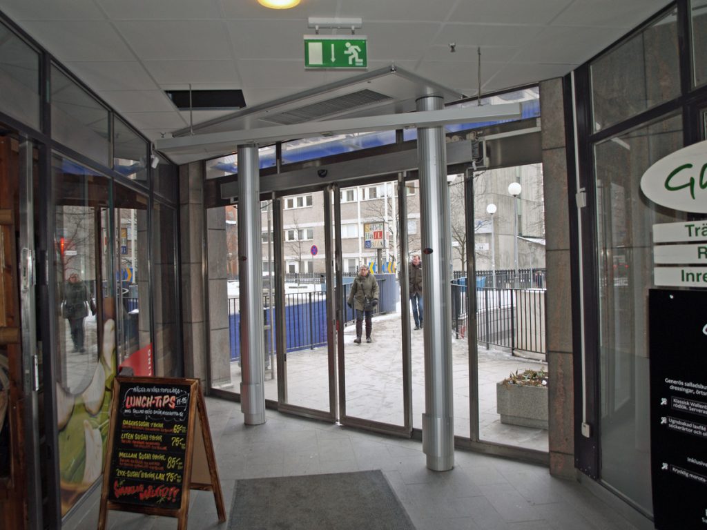 En sidoblåsande luftridå från RMK i en entré med skylt.