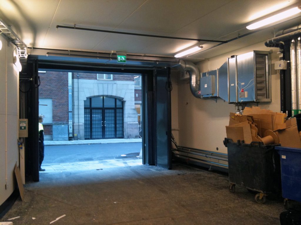 En ovanblåsande luftridå från RMK på industriport med sopbehållare.