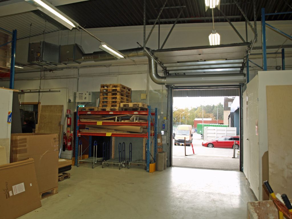 En ovanblåsande luftridå från RMK på industriport med röd bil.