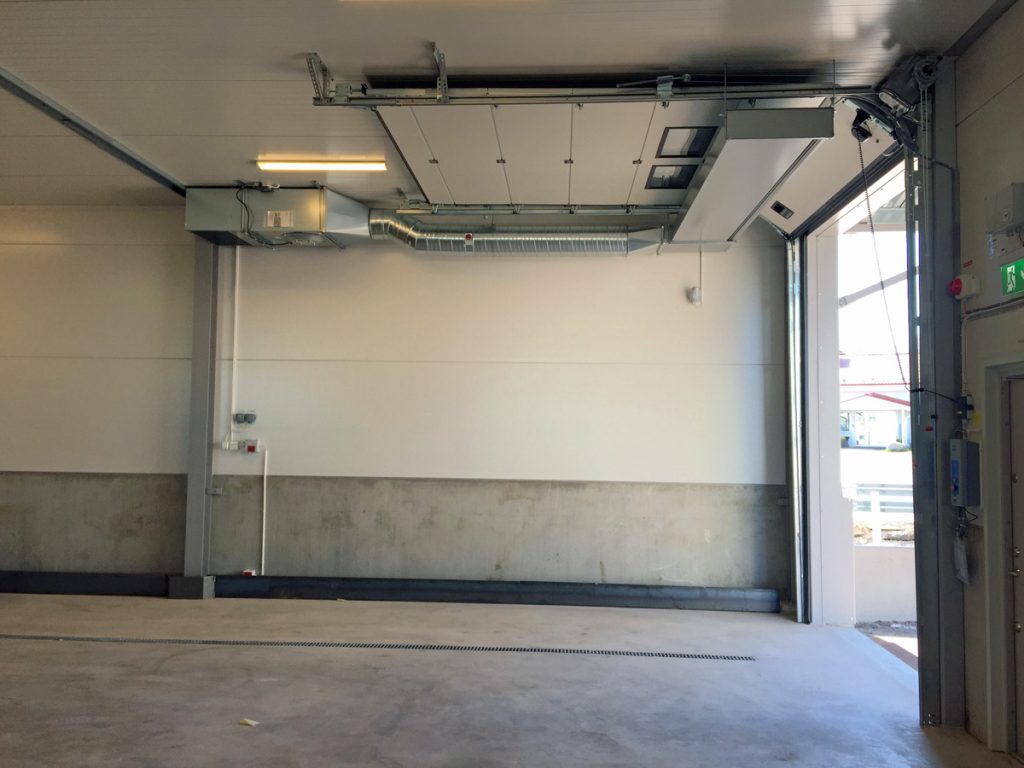 En ovanblåsande luftridå från RMK på industriport med vit övre vägg.