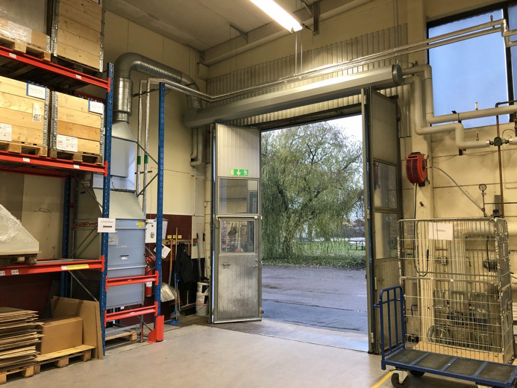 En ovanblåsande luftridå från RMK på industriport med hyllor.