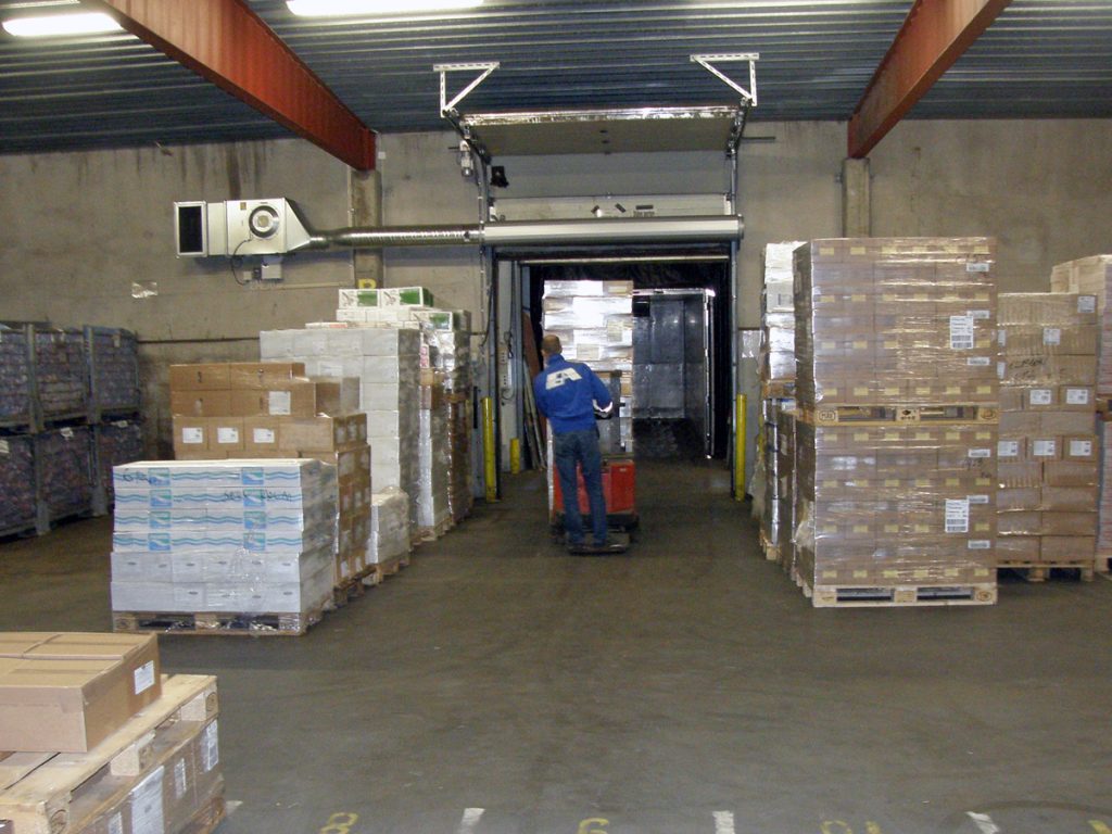 En ovanblåsande luftridå från RMK på industriport med truck mellan lastpallar.