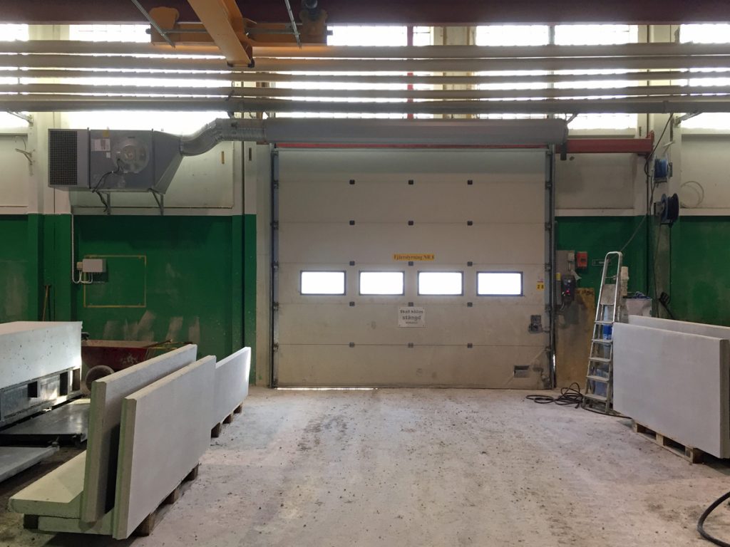 En ovanblåsande luftridå från RMK på industriport med stege och betongblock.