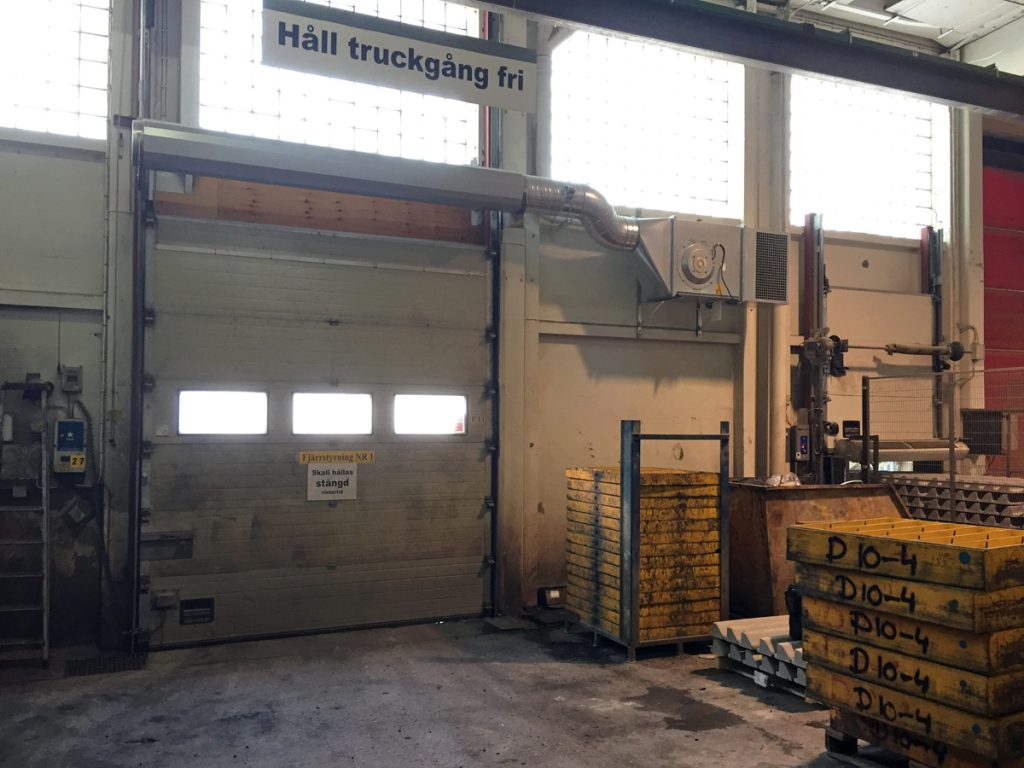 En ovanblåsande luftridå från RMK på industriport med skylt ovanför.