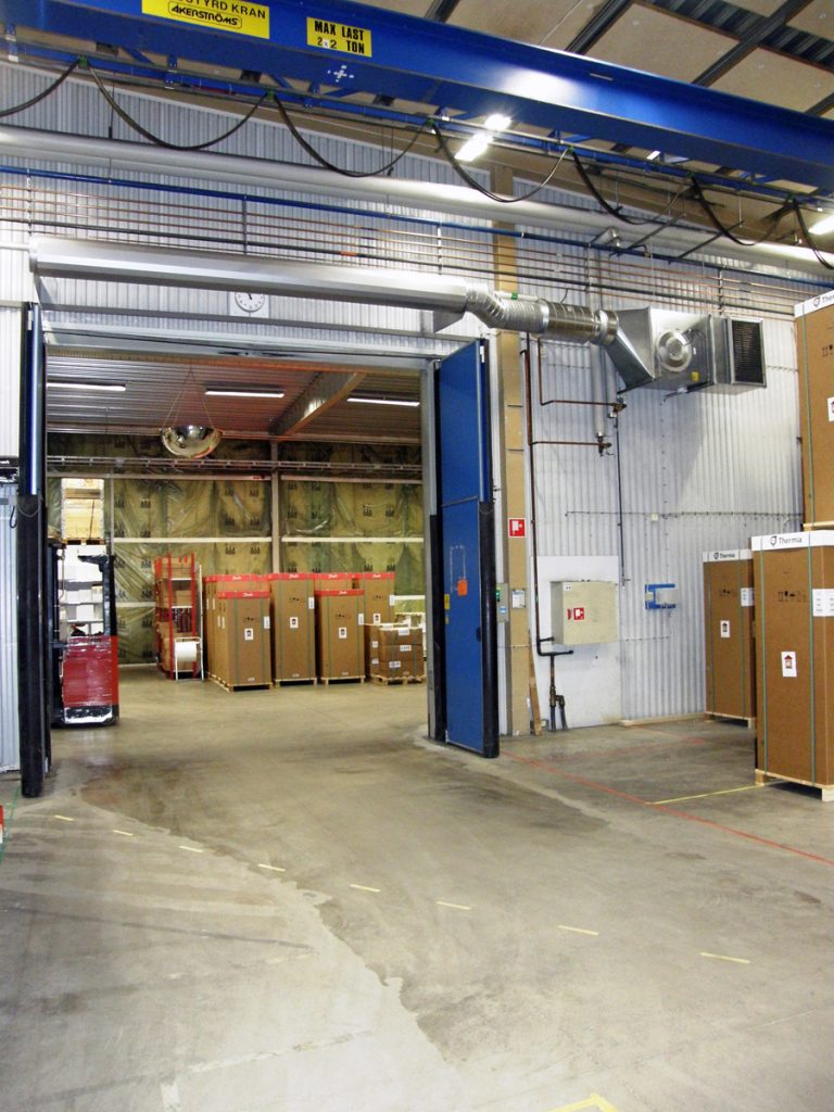 En ovanblåsande luftridå från RMK på industriport med blå vikdörrar.