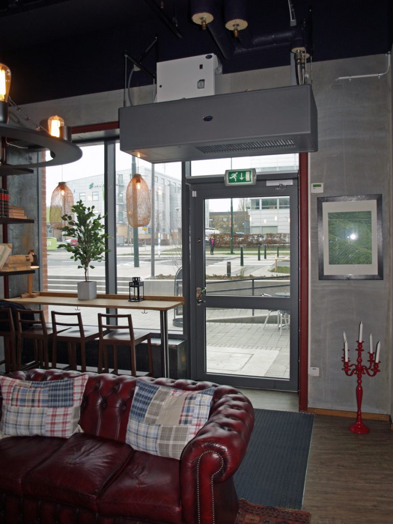 En ovanblåsande luftridå från RMK i en entré med soffa.