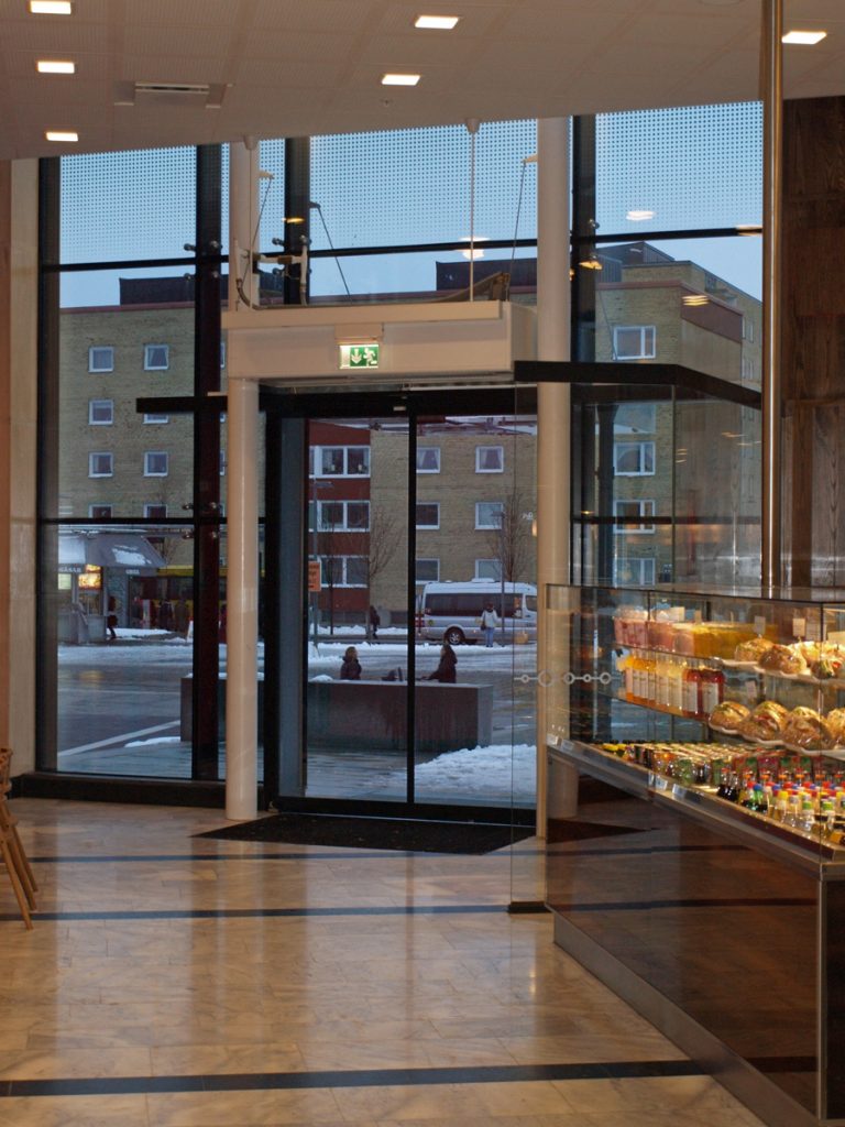 En ovanblåsande luftridå från RMK i en entré med vita pelare.