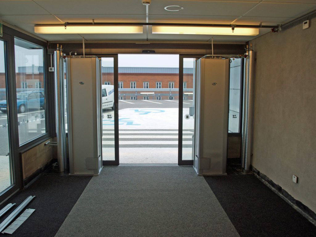 Sidoblåsande luftridåer från RMK i en entré med gul lampa.