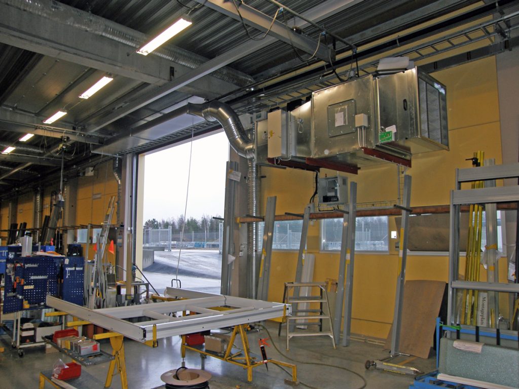 En ovanblåsande luftridå från RMK på industriport med gul vägg.