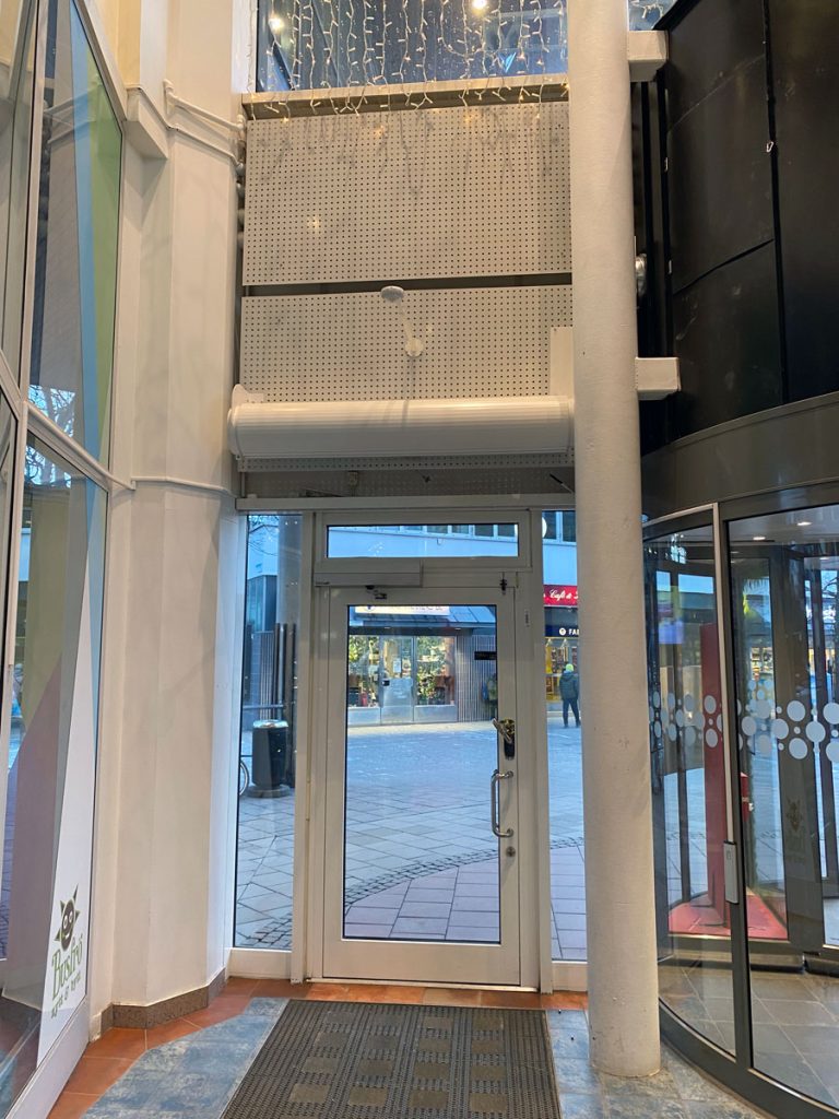 En speciallösning med luftridå från RMK på en karusell entré med vit dörr.