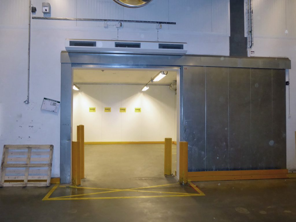 Ovanblåsande luftridå på ett kylrum med sidoport i stål.